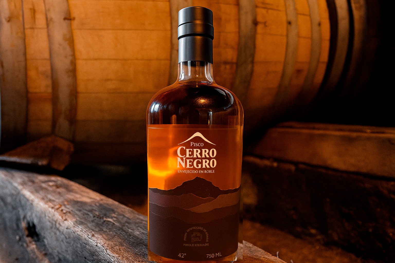 Botella de pisco chileno artesanal Cerro Negro junto a una copa